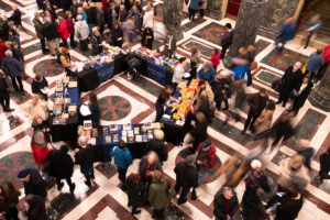 Photo of people gathering in the Music Hall lobby before a lecture. Many are buying books.
