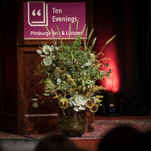 Photo of the podium at a Ten Evenings lecture with a beautiful arrangement of flowers